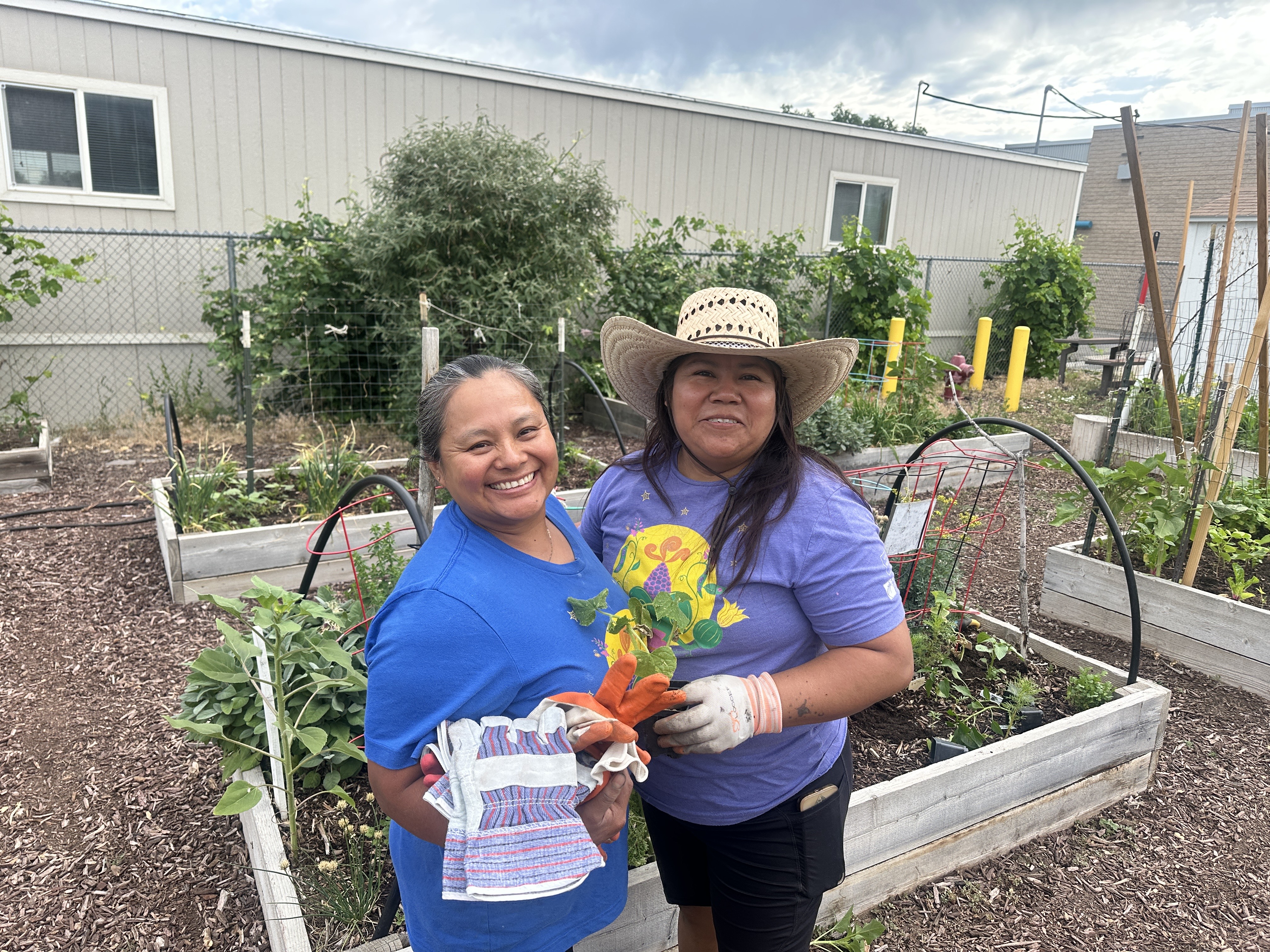 Two gardeners standing in front of their plots and smiling